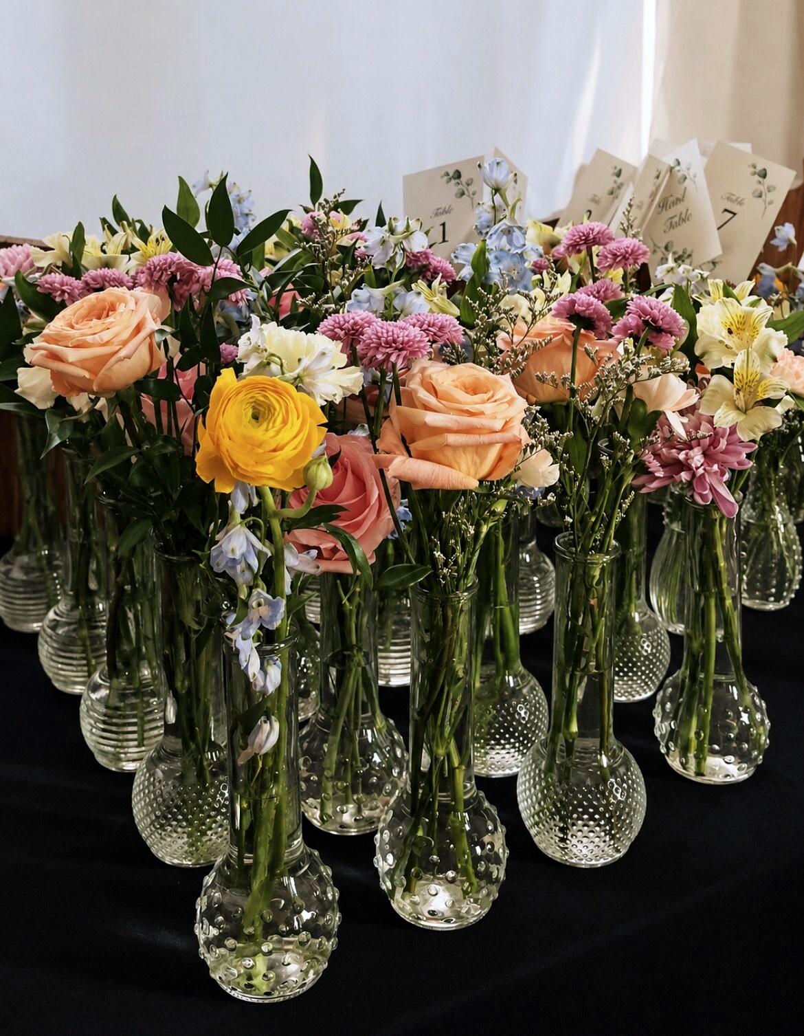 Bud vases of garden roses and ranunculus