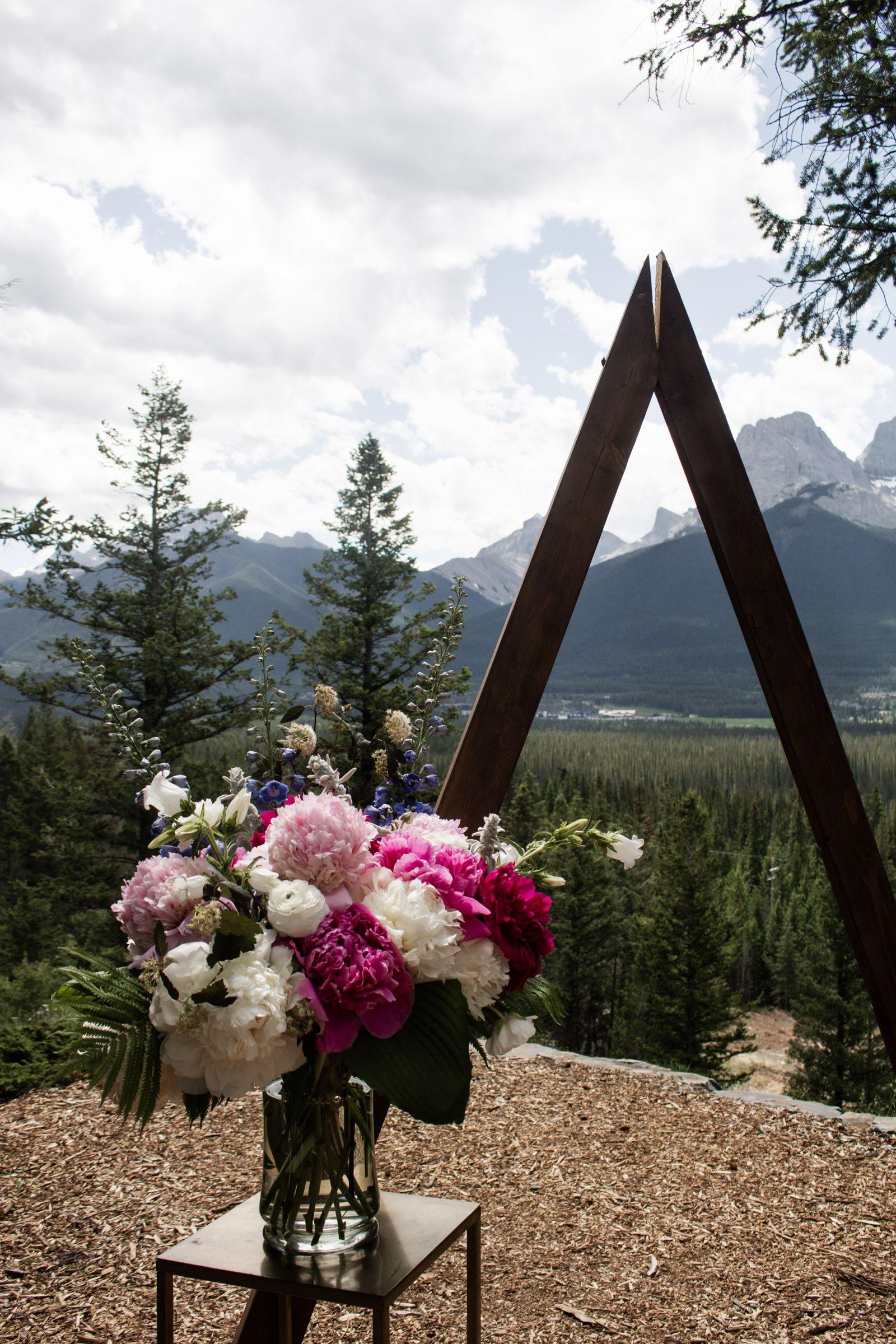 Peony arrangement at a ceremony arch with mountain views